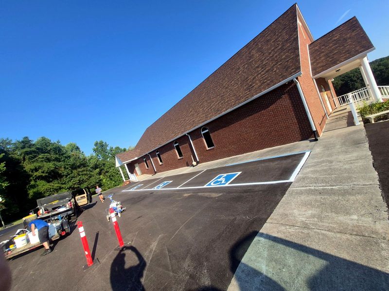 Freshly sealcoated parking lot beside a brick building with new ADA striping