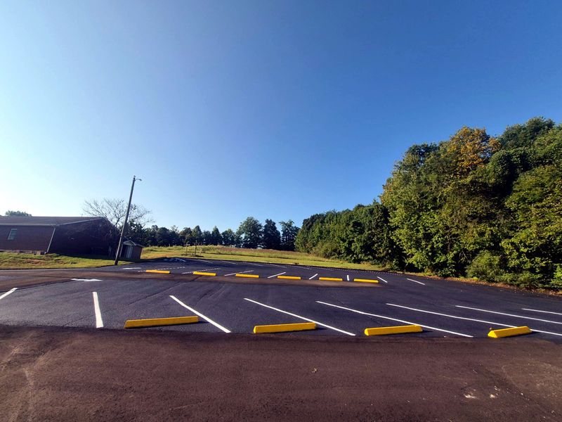 Commercial asphalt sealcoating project by Adams Bros Striping, finished with new striping and yellow wheel stops