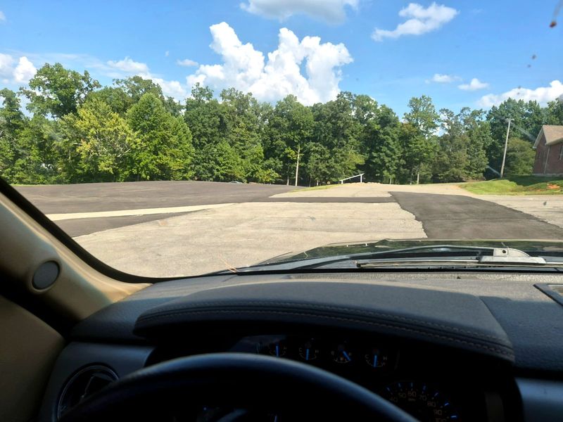 Commercial parking lot partway through sealcoating, with fresh sealcoat beside untreated asphalt
