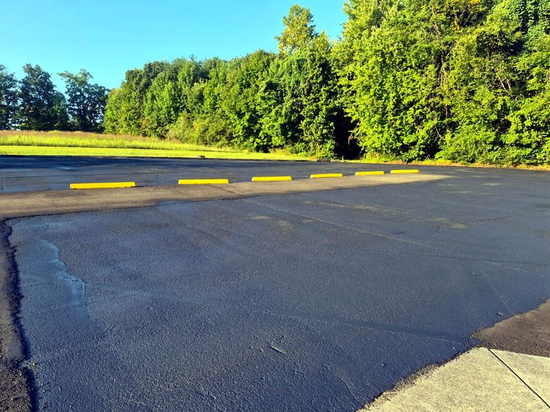 Close view of a finished sealcoated asphalt surface with yellow wheel stops
